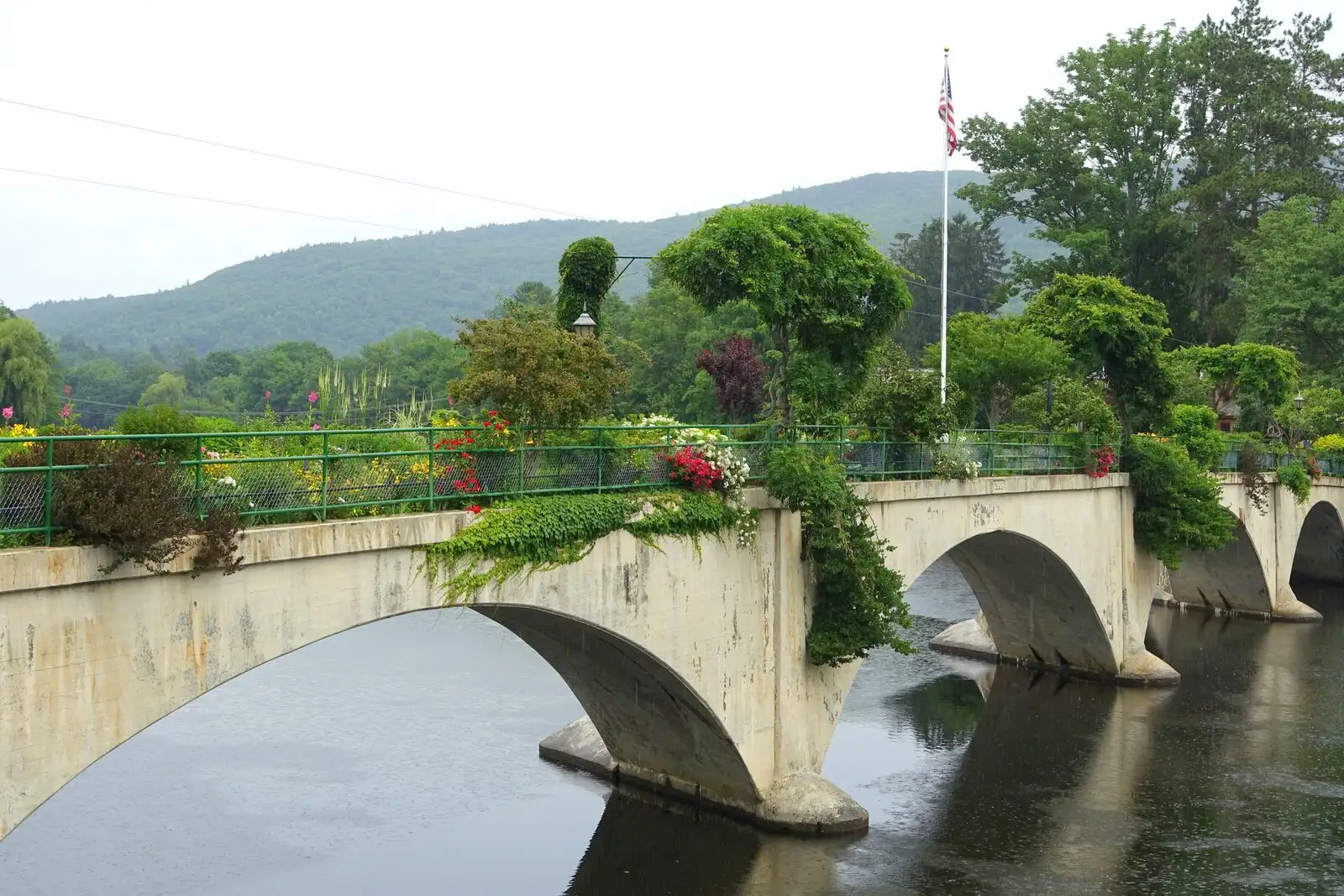 The Bridge of Flowers in Shelburne Falls: a former trolley bridge planted with summer perennials, with a US flag flying at the center.