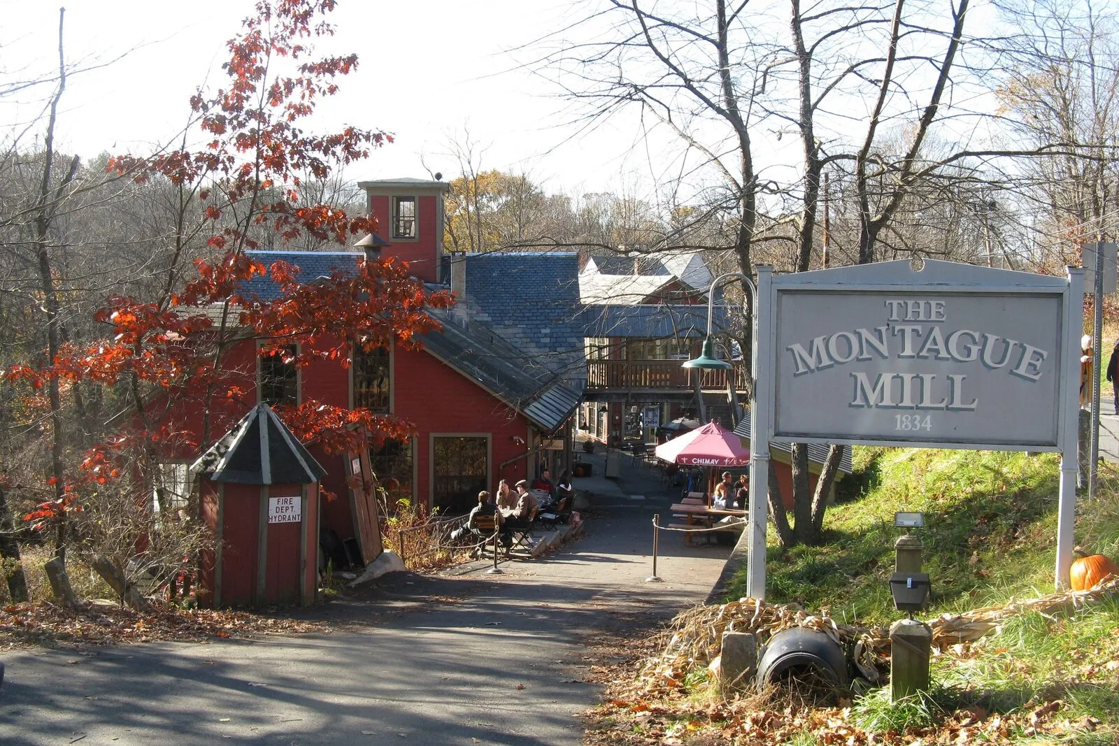 The Montague Bookmill, a tall clapboard mill building perched over the Sawmill River's stone dam, with the river sliding past in the foreground.