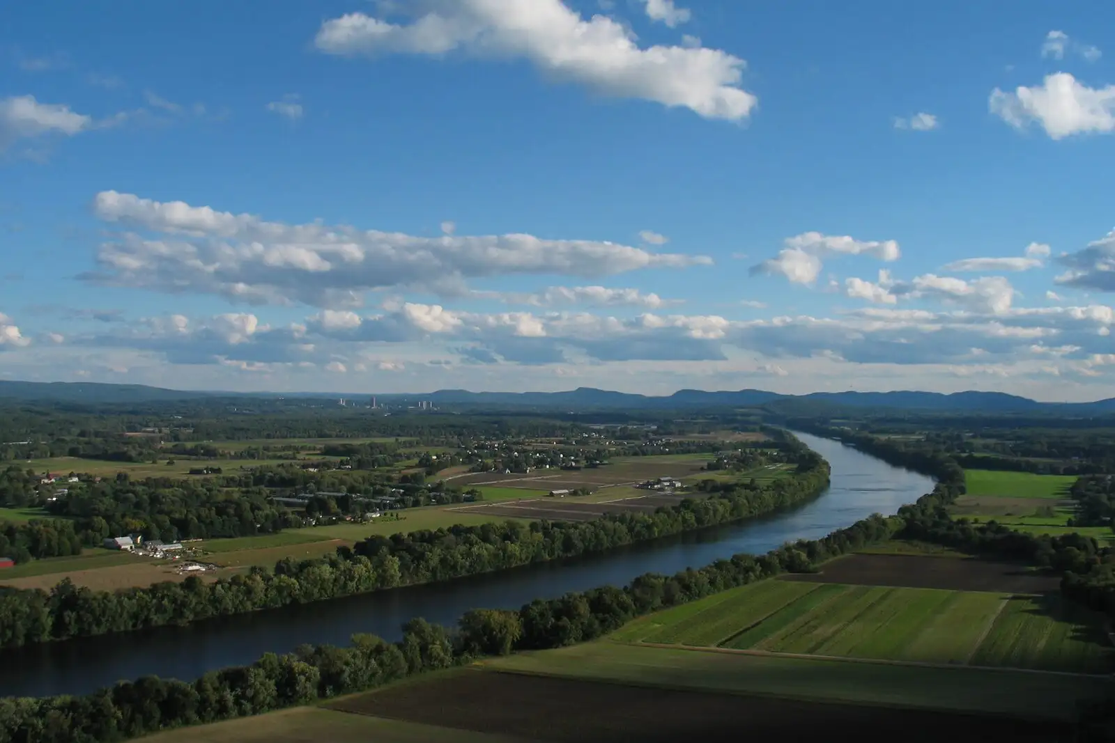 The Connecticut River Valley seen from the summit of Mount Sugarloaf: broad farm fields and the river winding south past the Holyoke Range.
